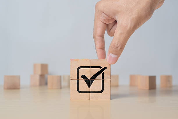 istock Hand placing tick sign on wooden block cube. Document approval, business project validation, and quality assurance concept 2218522685