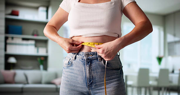 istock Smiling Young Woman Measures Weight Loss Progress 2218529298