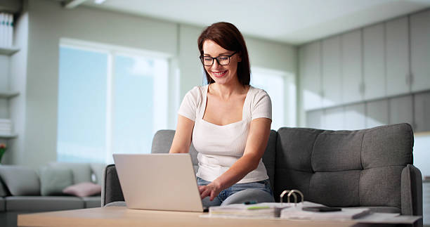istock Young Woman Calculating Finances Online On Couch With Bills 2218529335
