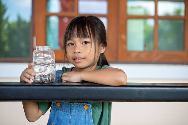 istock Smiling Young Girl Putting Coins in Jar 2218529413
