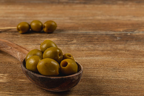 istock Delicious green olives in a wooden spoon on rustic table 2218533434