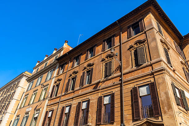 A yellow building with a lot of windows and balconies. The building is tall and has a lot of windows
