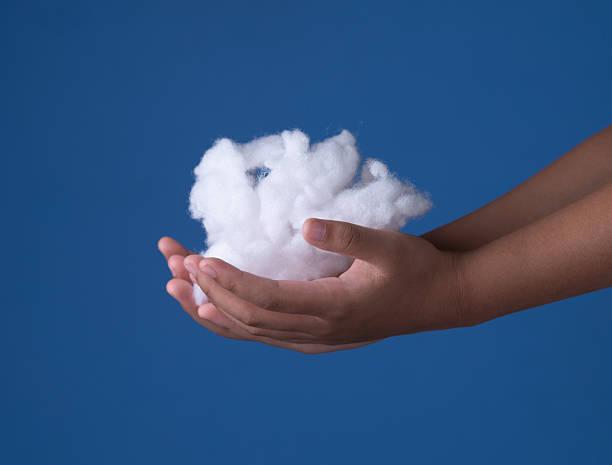 istock Siliconized hollowfiber, polyester fiber cloud held in a hand against a blue background 2218539845