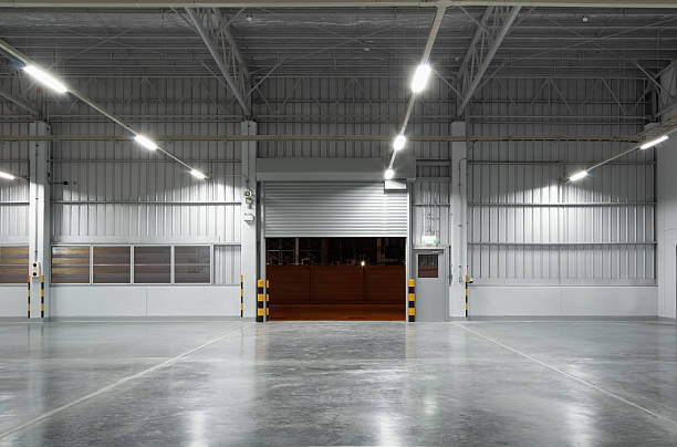 istock Concrete floor and shutter door inside industrial building at night. To construction for factory or warehouse. New clean and shiny surface. Nobody and empty space suit for product display background. 2218543589