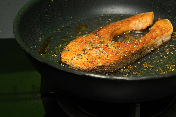 istock Salmon is being fried in a black iron pan with herbs, pepper and thyme. 2218545822