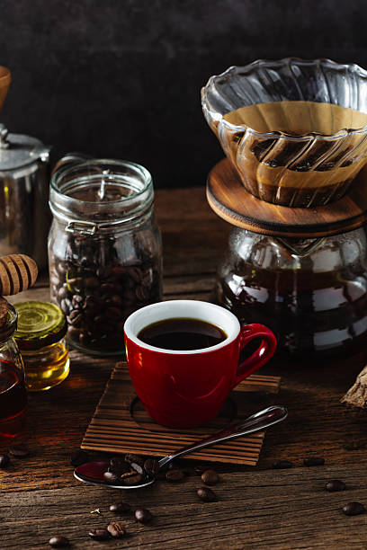 istock Fresh Brewed Coffee in Red Cup with Beans and Equipment Surrounding 2218547378