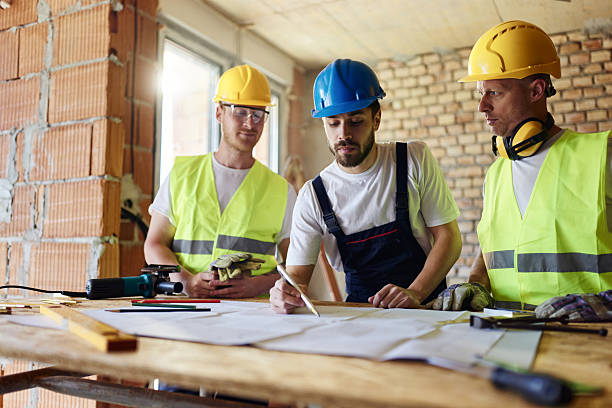 istock Team of manual workers examining housing project while working at construction site. 2218547834