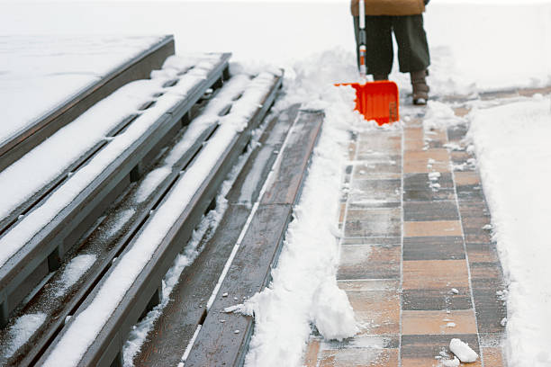 steps and granite floor covered with snow and sleet, a worker with a shovel standing in the blurred background
