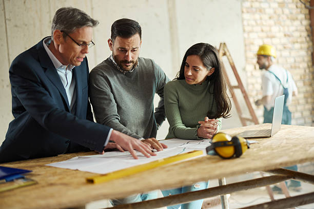 istock Young couple and their agent examining blueprints at construction site. 2218548342