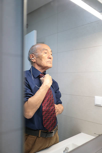 istock Senior businessman adjusting his tie in front of mirror, getting ready for work 2218552263
