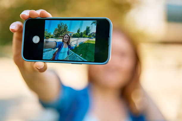 istock Young woman taking a selfie outdoors with smartphone 2218557816