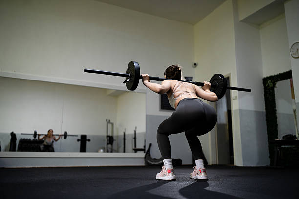 istock A muscular young woman in sportswear performs barbell back squats during a strength training session at the gym 2218558702