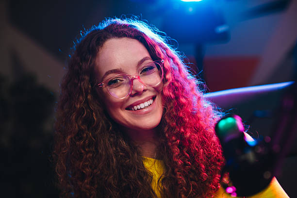 istock Young woman smiling confidently in a neon-lit studio using professional equipment for video and gaming content creation 2218560923