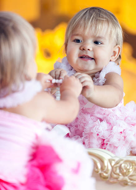 Little girl in pink dress playing on dressing table