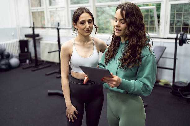 istock The fitness instructor presents a personalized exercise plan to her young female trainee, guiding her through each step with encouragement. 2218561960