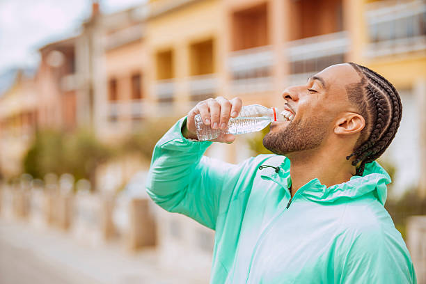 istock Happy sportsman drinking water after training outside 2218564516