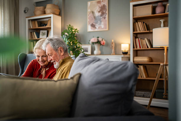 istock Happy senior couple relaxing on sofa browsing internet on digital tablet at home 2218565448