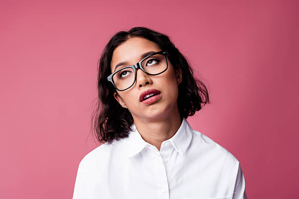 Charming woman in formal white shirt with expressive face showing amusing gesture against vibrant pink background