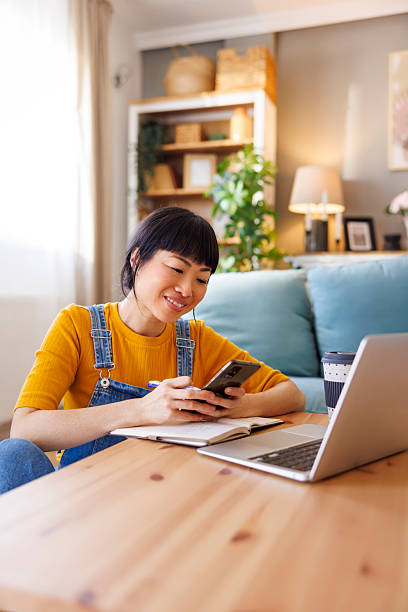 istock Woman using smart phone and laptop computer while working from home 2218575023