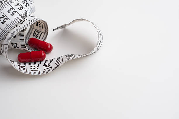 istock Measuring tape and tablets, vitamins on a light background with space for text. Concept of losing weight, dieting, burning fat, healthy eating. 2218582789