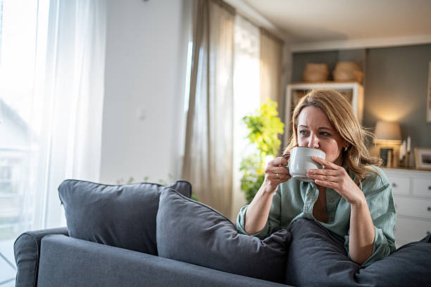 istock Woman relaxing on sofa drinking tea in living room 2218583110