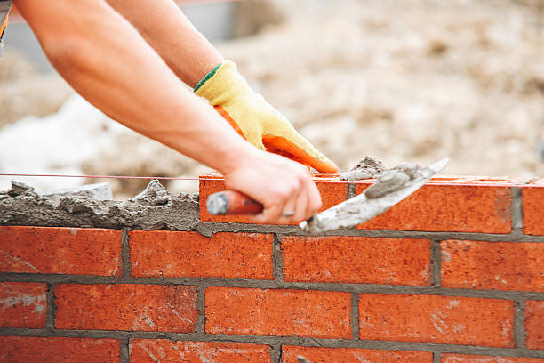 istock Close-up of skilled bricklayer working on construction site laying red bricks for wall construction 2218587109