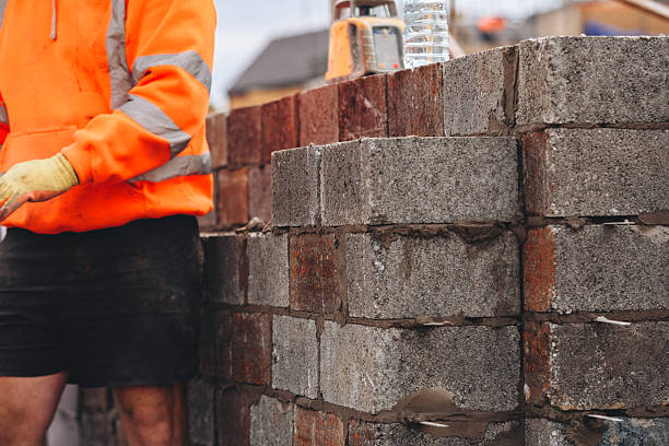 istock Close-up of Construction worker laying concrete blocks on building site 2218587254