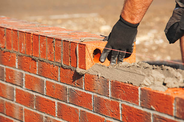 istock Close-up of skilled bricklayer working on construction site laying red bricks for wall construction while 2218587931