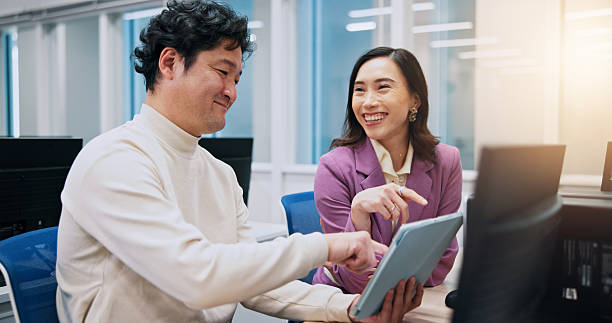 istock Collaboration, pointing and tablet with business people in office for creative, design or web development. Feedback, laughing or funny with Japanese man and woman in workplace for discussion 2218588366