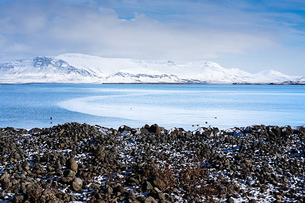 istock Winter landscape: snowy mountains, icy water, rocky shore. 2218593231