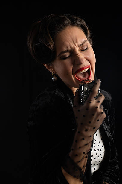 istock Woman Singing Passionately Into Vintage Microphone On Stage 2218595596