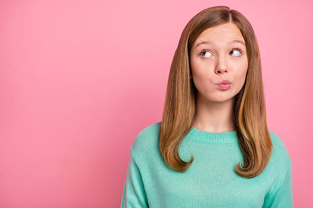 istock Photo of doubtful school girl dressed teal pullover looking empty space isolated pink color background 2218595815