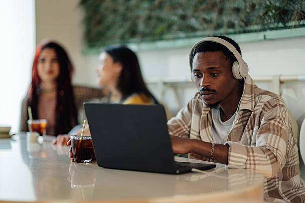 istock Focused young man working on laptop in cafe with headphones 2218596111