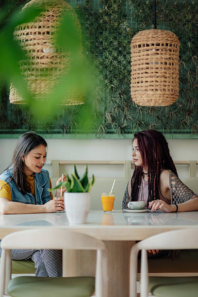istock Two young women talking and drinking in a modern cafe 2218596152