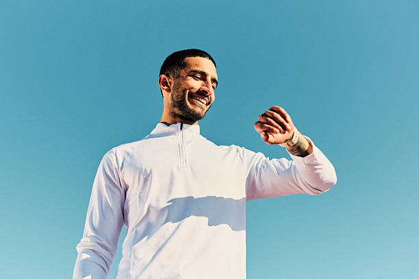 Young man looking at smartwatch against clear blue sky