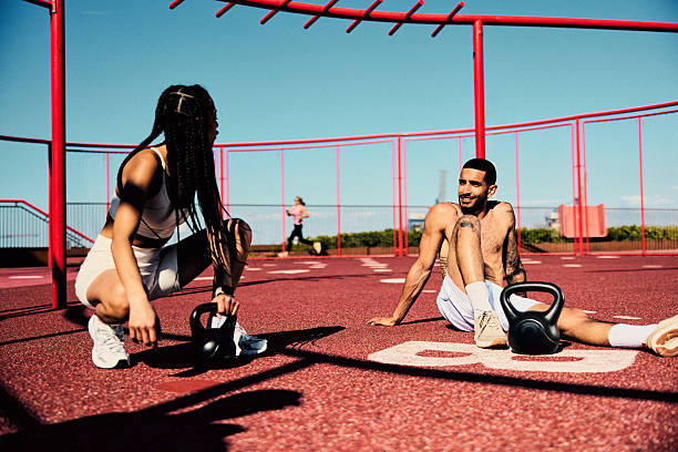 istock Active young couple sitting on floor outdoors with kettlebells, resting and chatting 2218596850