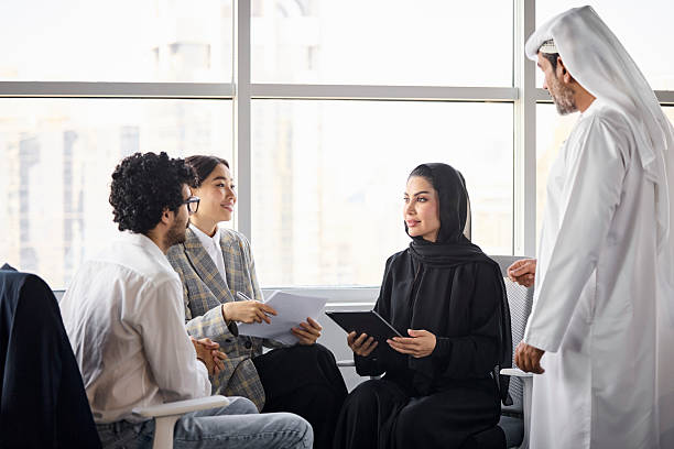 Multiracial business experts analyzing sales report. Male and female entrepreneurs are discussing ideas with each other. They are in meeting at office.