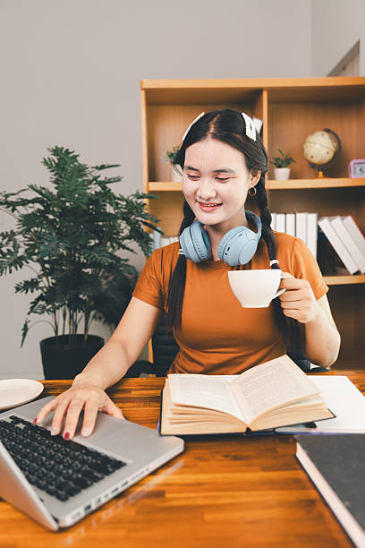 istock woman sitting at desk working on laptop taking notes in notebook, female studying online, watching webinar using computer, writing check list. Remote college school education, e learning concept. 2218600421