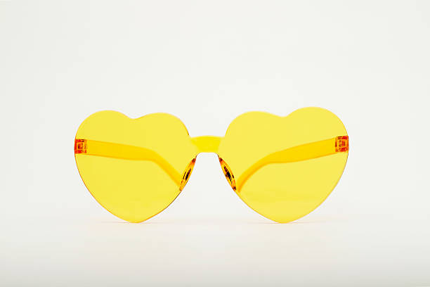 istock Yellow heart-shaped sunglasses resting on white background 2218605691