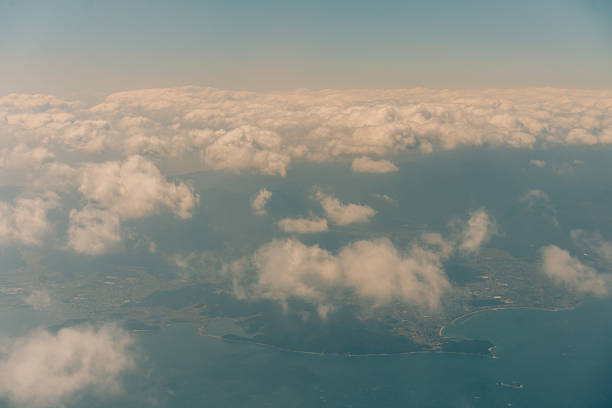Aerial view through the clouds to the sea bay with coastal hills. Top view from the clouds to Japan islands. High quality photo