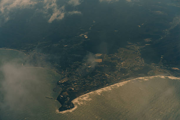 Aerial view through the clouds to the sea bay with coastal hills. Top view from the clouds to Japan islands. High quality photo