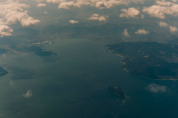 Aerial view through the clouds to the sea bay with coastal hills. Top view from the clouds to Japan islands. High quality photo