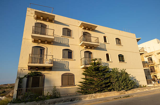 A street located in the coastal village of Marsalforn, situated on the island of Gozo, Malta. Marsalforn is known for its scenic bay, making it a popular destination for both locals and tourists. Logos and insignia are visible.