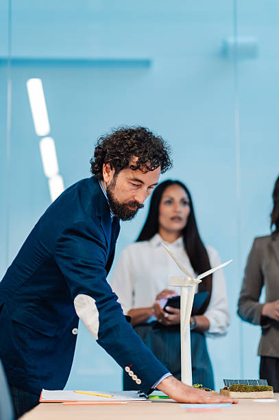 istock Businessman analyzing wind turbine and solar panel models in meeting 2218621570