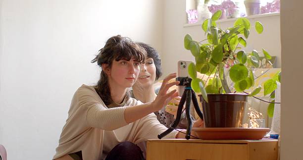 Two Women Joyfully Posing for a Fun Photo with a Camera on a Tripod