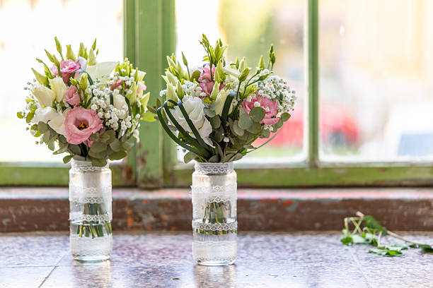 Two wedding bouquets with pink and white lisianthus and gypsophila are resting on a windowsill