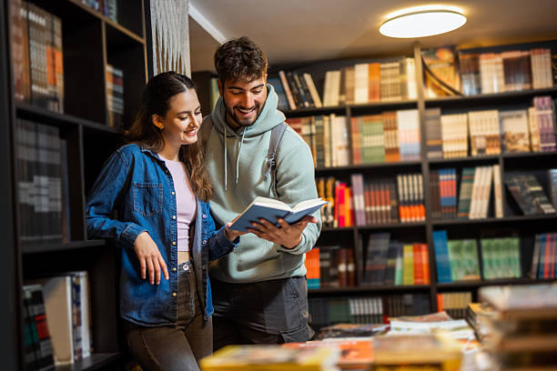 istock Two students read a book in the library together. 2218625601