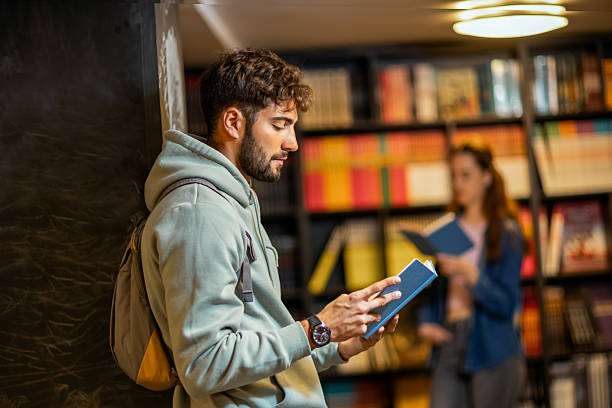 istock Focused Male Student Reading a Book in the Library 2218625995