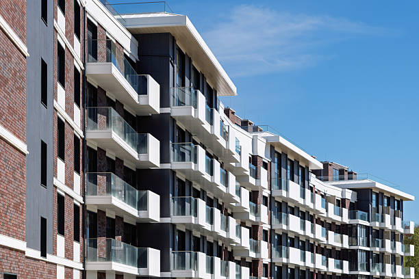 istock Modern residential building with glass balconies and brick facade stands under clear blue sky, symbolizing urban comfort and contemporary living. 2218629310