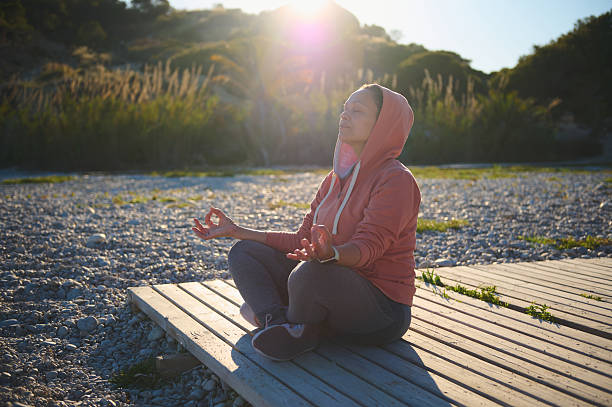 Woman Meditating Outdoors on a Wooden Platform During Sunset